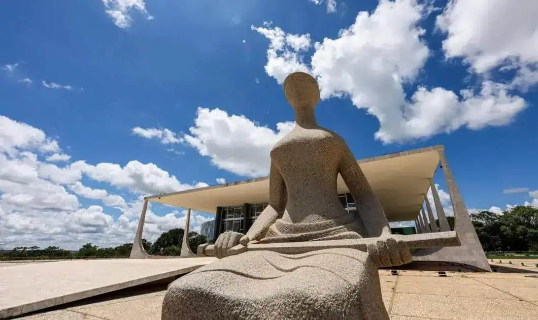 Estátua de justiça moderna em frente ao Congresso Nacional de Brasília, símbolo da luta pelos direitos e a justiça social no Brasil. Arquitetura contemporânea e cultura jurídica brasileira em destaque.
