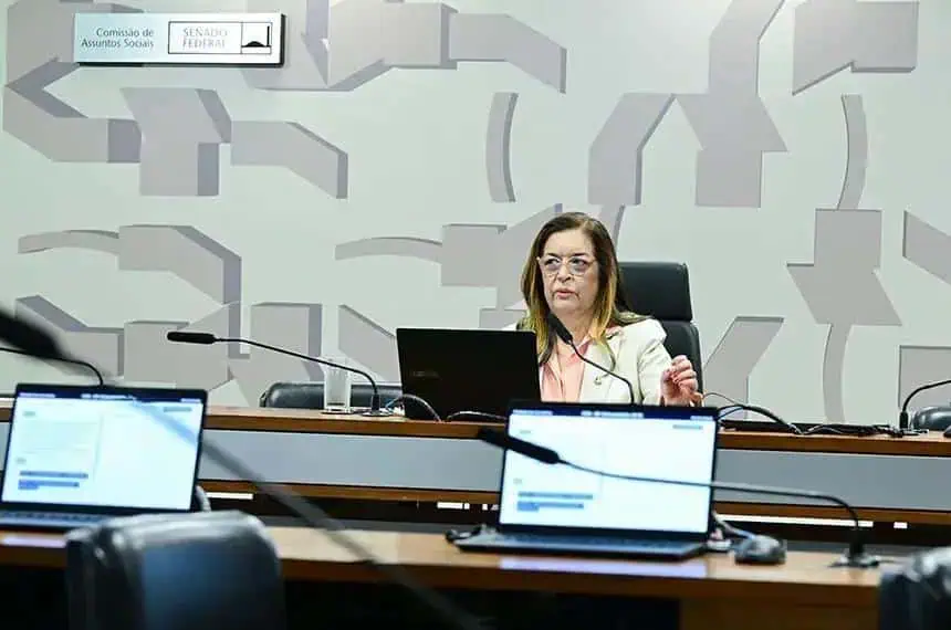 Legislação e debates no Congresso Nacional sobre justiça, direito e assuntos sociais no Brasil. Imagem de uma mulher participando de reunião no plenário, com computadores e painel ao fundo.