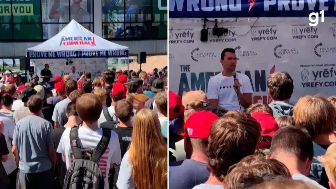 Ativistas protestando em evento político com grande público em frente ao palco ao ar livre.
