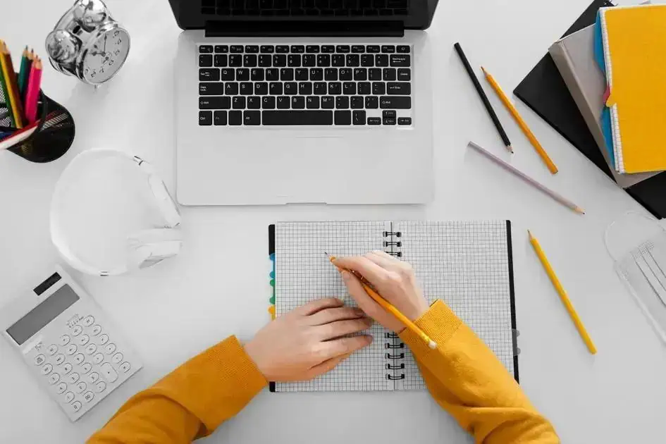 Estudante organizando materiais de estudo e computadores em mesa de trabalho, representando pesquisa e aprendizado em direito, ideal para artigos de notícias e atualizações legais.