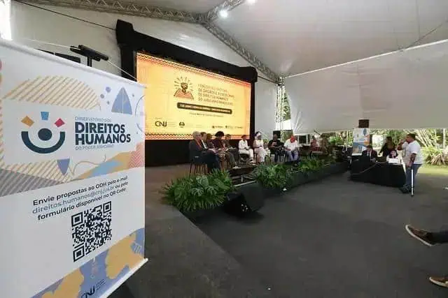 Direito Hoje Notícias evento de discussão de direitos humanos com painel de especialistas sob tenda ao ar livre.