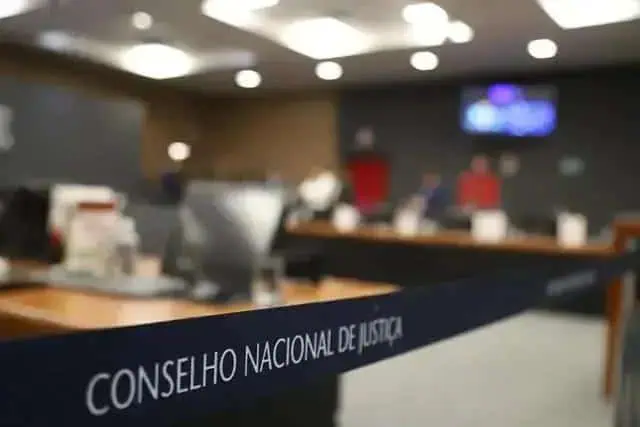 Conselho Nacional de Justiça em sessão de julgamento com ambiente formal e pessoas ao fundo, relacionada às notícias de direito hoje no portal Direito Hoje Notícias.