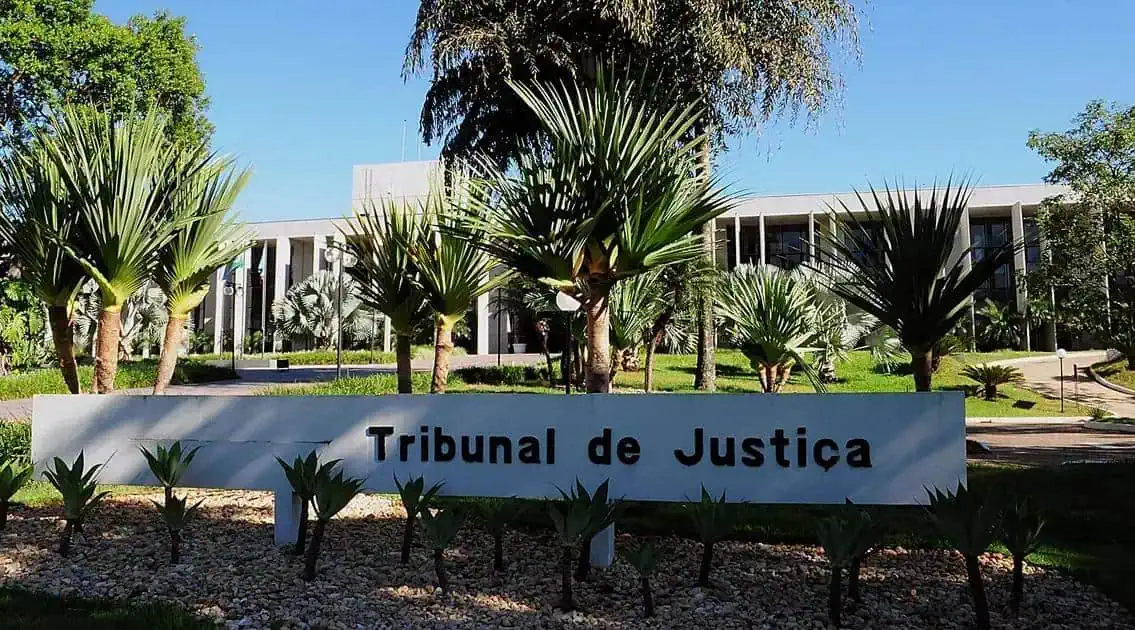 Tribunal de Justiça em frente ao edifício, com jardim de plantas ornamentais e árvores, símbolo da justiça e do direito no Brasil, destaque para a fachada moderna e bem cuidada, ideal para notícias de direito e justiça.