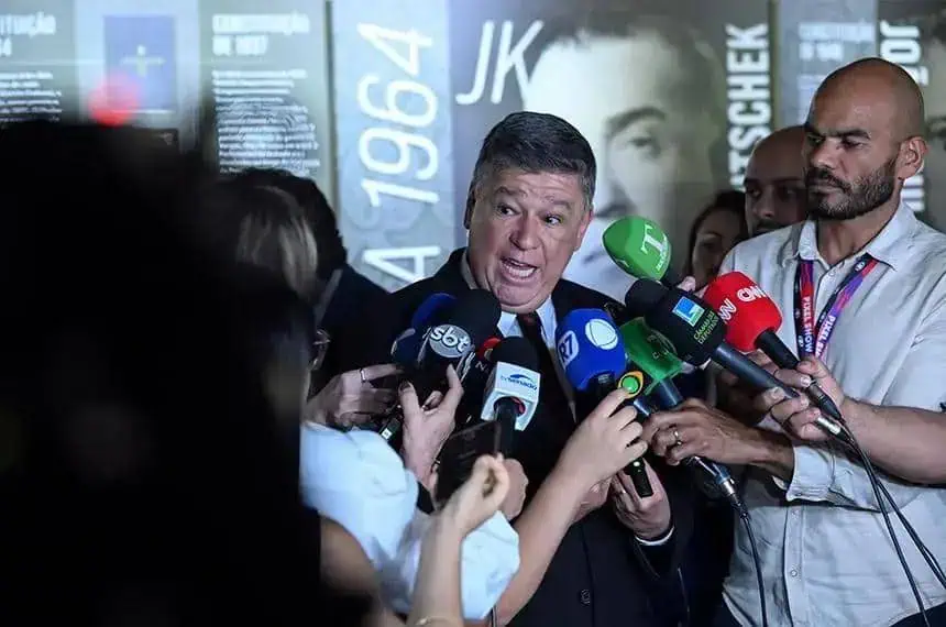Vereador dando entrevista para a imprensa com vários microfones de canais de notícias diferentes ao seu redor.