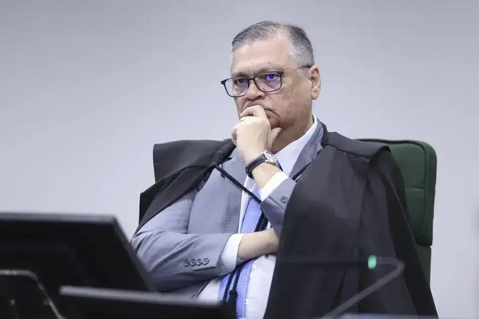 Juiz de direito em tribunal, vestindo toga e gravata, analisando processo judicial com expressão pensativa e concentrada, representando o setor jurídico e o direito hoje notícias.