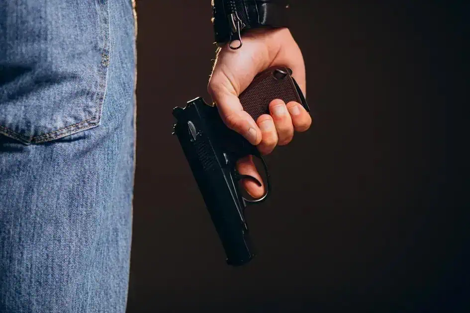 Arma de fogo sendo manuseada por uma pessoa, ilustrando temas de segurança e legislação policial no contexto do Direito Hoje Notícias.