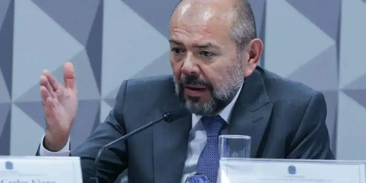 Advogado hablando durante conferência sobre direito e notícias jurídicas em ambiente formal.