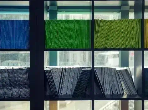 Arquivos de documentos organizados em estantes de escritório, de diversas cores.