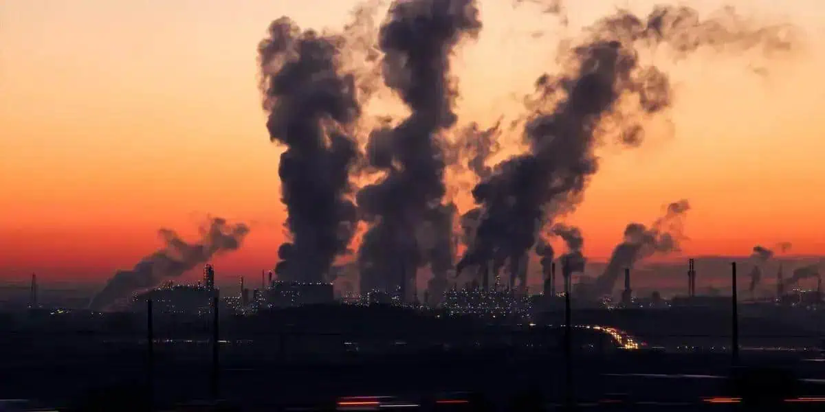 Poluição industrial com fumaça saindo de fábricas ao entardecer, impacto ambiental e questões jurídicas relacionadas à proteção do meio ambiente no Brasil.