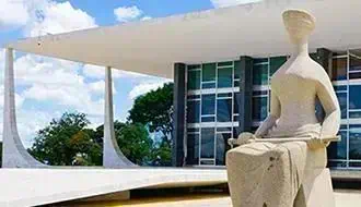 Estátua de mulher moderna sentada em frente ao edifício do Supremo Tribunal Federal em Brasília, representando justiça e direito no Brasil.