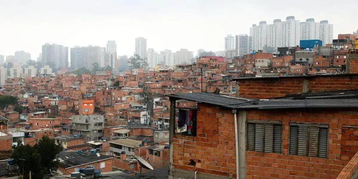 Favelas urbanas com prédios altos ao fundo, mostrando desigualdade social, moradia precária e desafios territoriais, tema destacado em notícias de direito e políticas públicas.