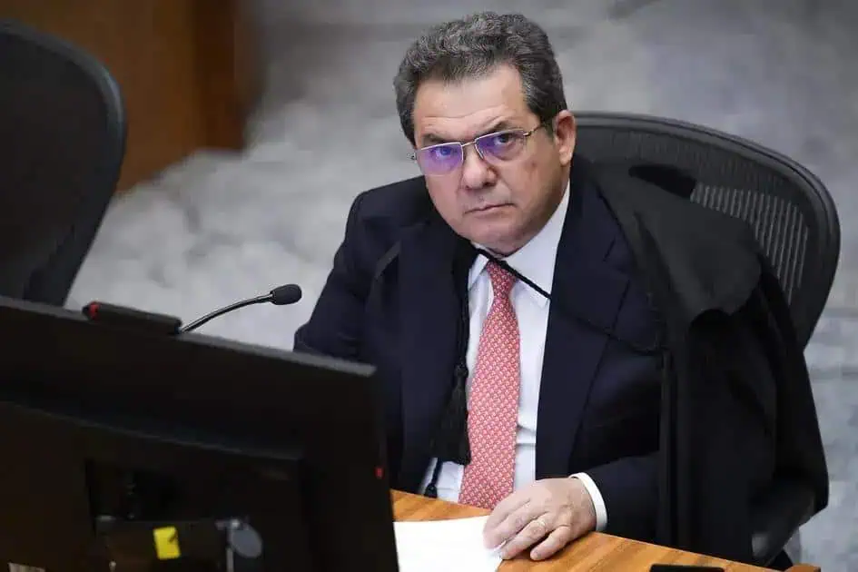 Analista judicial sentado em tribunal com traje formal e expressão séria, representando o tema de direito, jurisprudência e notícias jurídicas no Brasil.