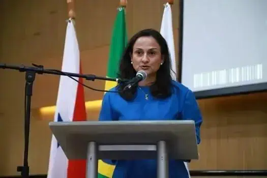 Usuária fala na tribuna durante evento de Direito Hoje Notícias, com bandeiras do Brasil, Estados Unidos e Brasil ao fundo, reforçando temas de direito e justiça.