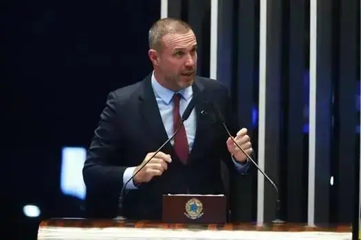 Homem em traje formal fala em plenário, representando autoridade ou participante de debate jurídico.