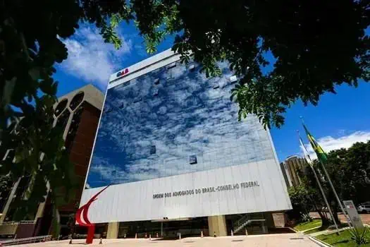 Edifício do Congresso Nacional do Brasil com fachada moderna refletindo o céu e as nuvens.