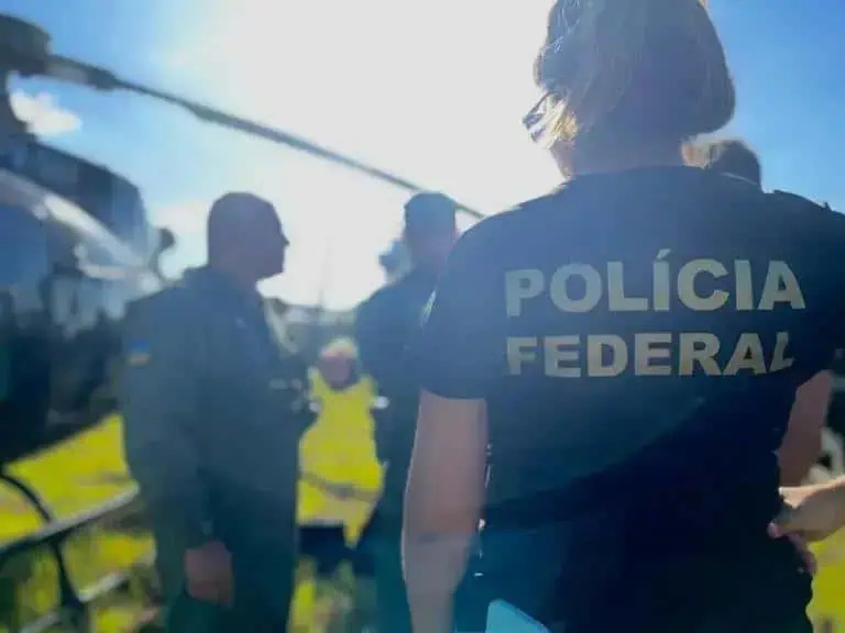 Polícia Federal atuando em investigação criminal na rua com equipe policial ao fundo.