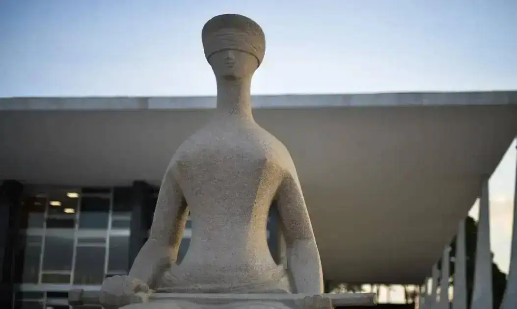 Estátua de mulher em posição de meditação ou yoga em frente a um prédio moderno, simbolizando paz, equilíbrio e bem-estar, temas relacionados a direito, justiça e saúde no contexto de notícias jurídicas.