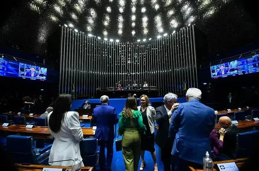 Alo histórico de uma sessão de tribunal ou assembleia legislativa com pessoas conversando, incluindo mulheres e homens, ambiente formal e moderno com iluminação e telas digitais ao fundo.