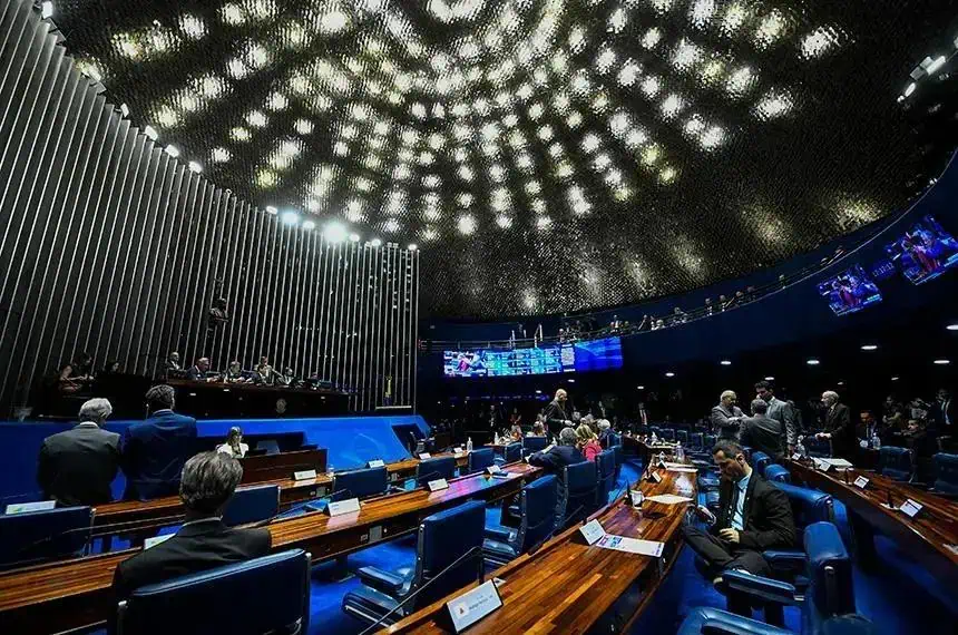 Político discutindo em plenário de congresso nacional em ambiente moderno e formal, com destaque para a cúpula de teto iluminada e tecnologia avançada, representando temas de Direito, política e leis.