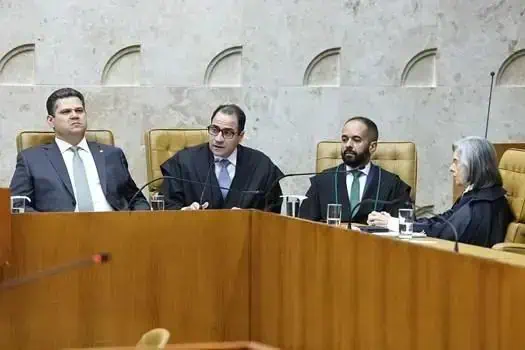 Julgamento no tribunal com juízes e advogados no plenário, incluindo uma mulher idosa, em sessão relacionada ao direito e às notícias atuais do setor jurídico.