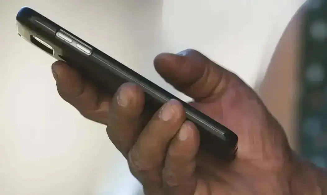 Celular smartphone preto sendo segurado por mão de pessoa, foco no aparelho, tecnologia, comunicação, direito hoje notícias.