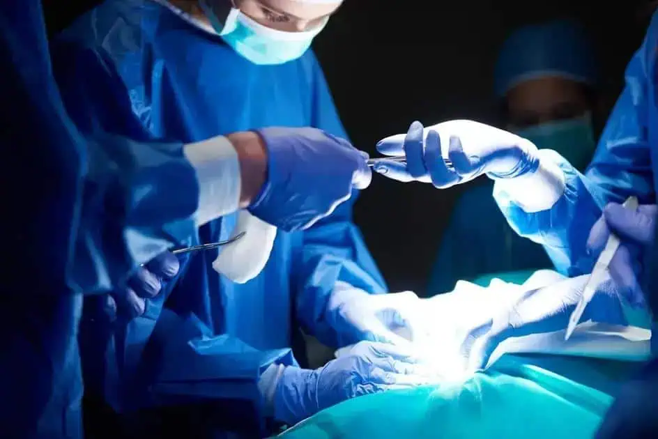 Cirurgiões realizando procedimento cirúrgico em ambiente de hospital com equipamentos médicos de alta tecnologia.