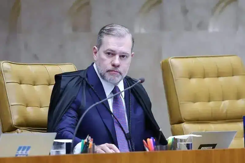 Juiz de tribunal federal em sessão de julgamento, sentado em cadeiras de tribunal, representando o direito e a justiça, com expressão séria e profissional, com cadeira destaque e documentos ao seu redor.
