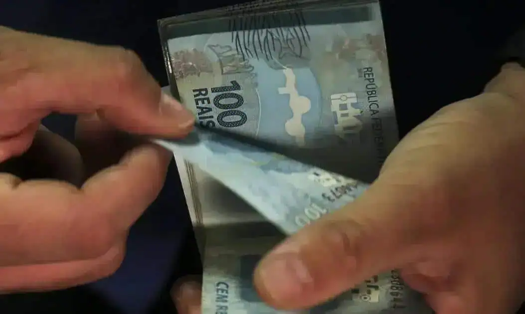 Dinheiro em cédulas de 100 reais sendo contado, foco em economia e finanças, destaque para legislação e notícias de direito hoje.