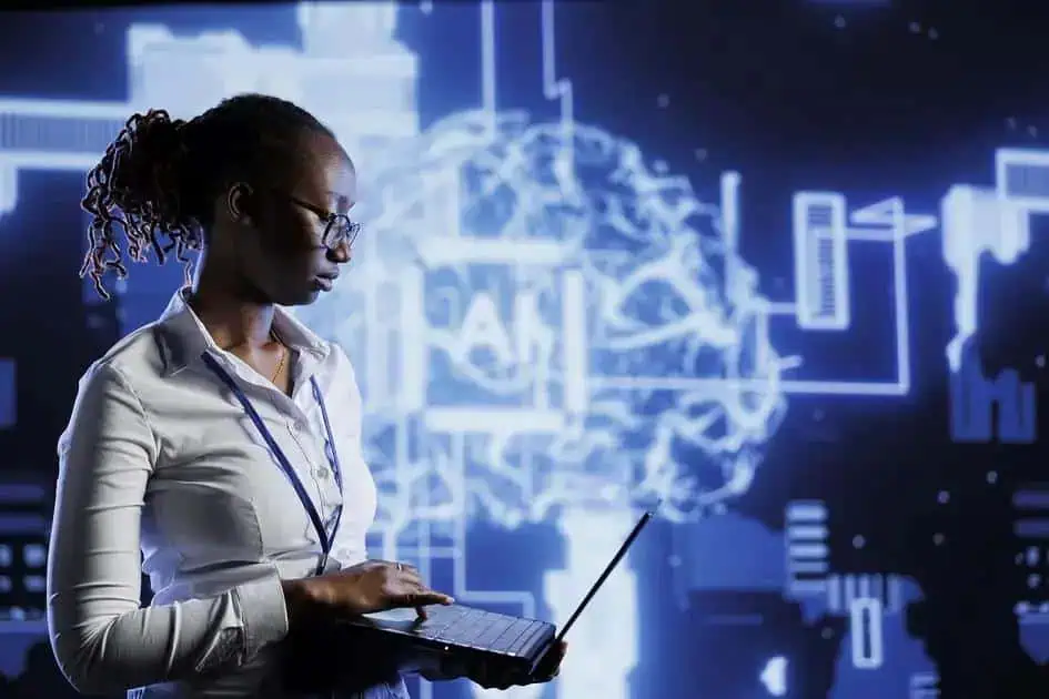 Análise de imagem: Mulher negra usando óculos e laptop, diante de fundo com elementos tecnológicos e cérebro digital, simbolizando inovação e tecnologia na área jurídica e de notícias.