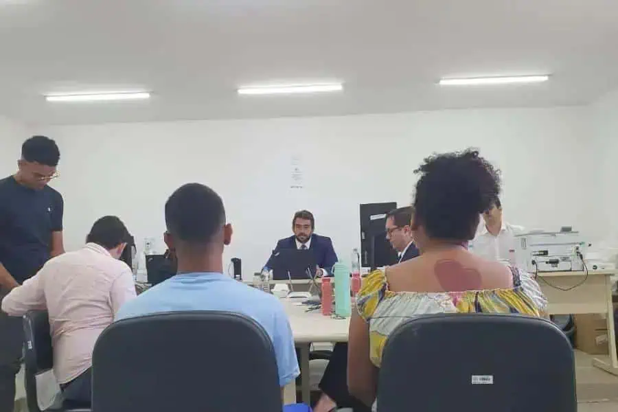 Audiência jurídica em uma sala de reuniões com profissionais do direito e clientes, abordando temas legais e judiciais.