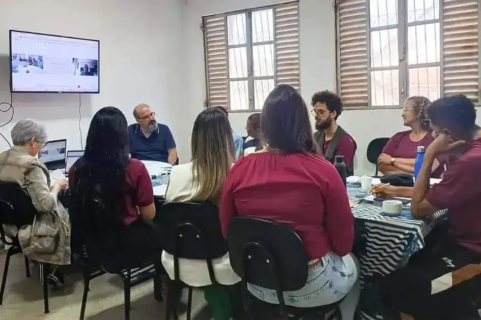 Profissionais participam de reunião ou workshop em ambiente de escritório, com discussão e uso de tecnologia para atualização jurídica e notícias de direito, promovendo debates sobre temas relevantes na área jurídica.