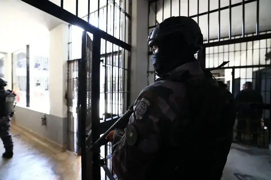 Operação policial em ambiente de prisão, integrantes da força de segurança armados e atentos.