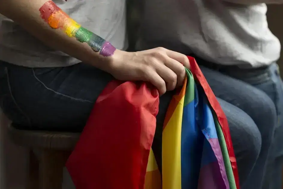 Organização LGBTQ+ com bandeira colorida e tinta na pele, refletindo temas de direitos e inclusão.