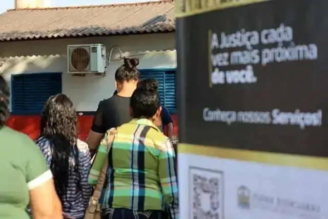 Aparelhos de ar-condicionado instalados em fachada de prédio acadêmico, com pessoas caminhando na rua, em ambiente urbano durante o dia, com atmosfera de rotina e atividades cotidianas ligadas ao direito e justiça.