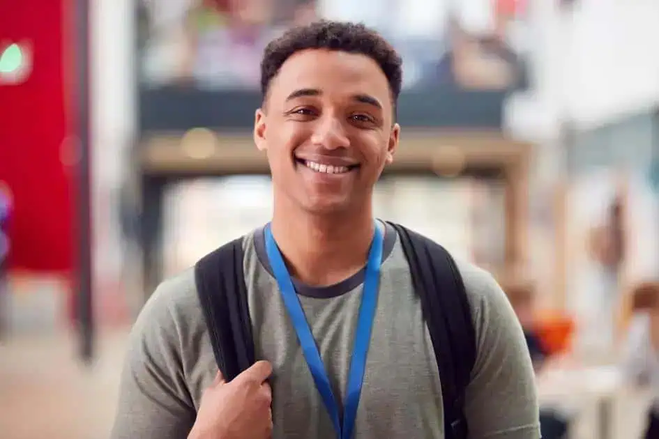 Estudante sorridente com mochila em ambiente acadêmico, representando direito, educação, estudantes e notícias de direito hoje.