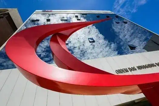 Edifício da Ordem dos Advogados do Brasil (OAB) refletindo o céu, simbolizando autoridade jurídica e advocacia no Brasil. Fachada moderna e imponente, destaque na cena urbana relacionada ao Direito e à Justiça.