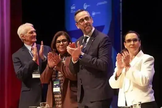 Profissionais do Direito em celebração ao evento jurídico, demonstrando reconhecimento e entusiasmo em ambiente formal de conferência ou seminário.