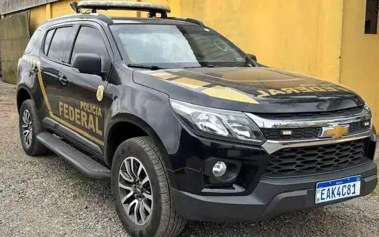 Polícia Federal Chevrolet S10 blindada com detalhes em verde e amarelo estacionada em frente a uma parede amarela, destacando operações de segurança e combate ao crime.