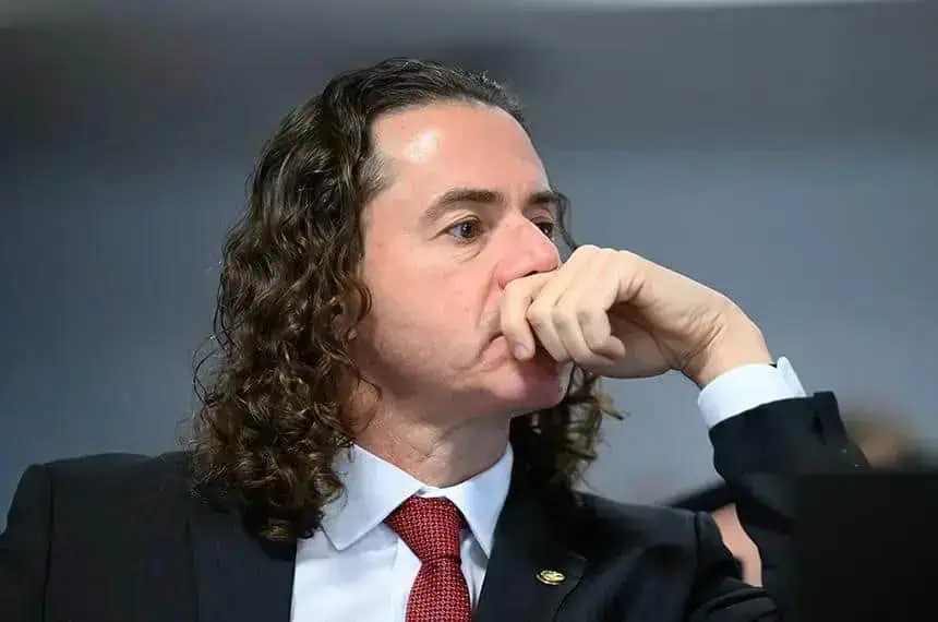 Inspetor de justiça pensativo durante sessão no tribunal, usando terno, demonstrando reflexão sobre questões jurídicas e de direito na sala de audiência.