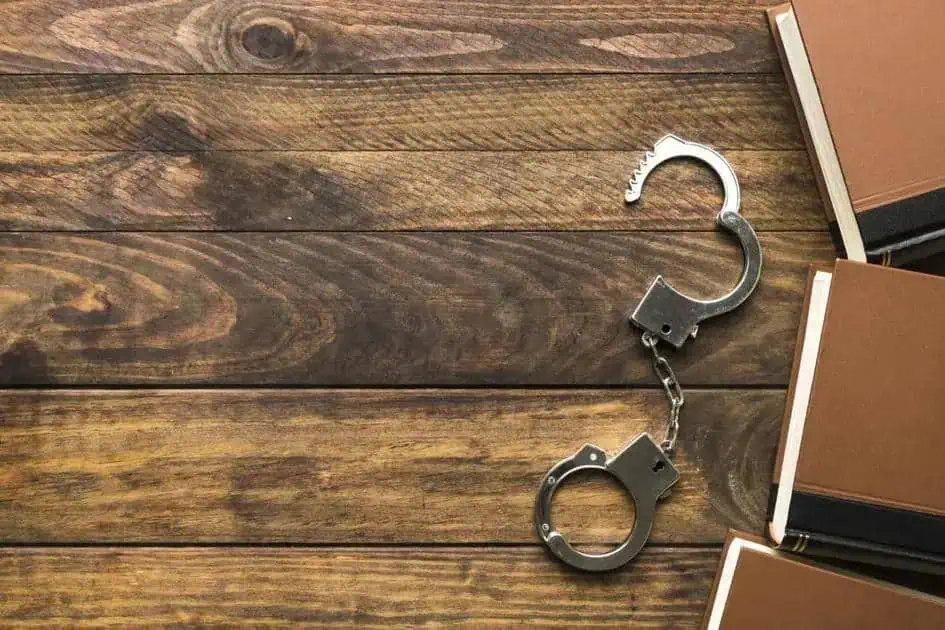 Cadeia de mãos dadas sobre uma mesa de madeira, simbolizando direitos, justiça e liberdade no contexto jurídico.