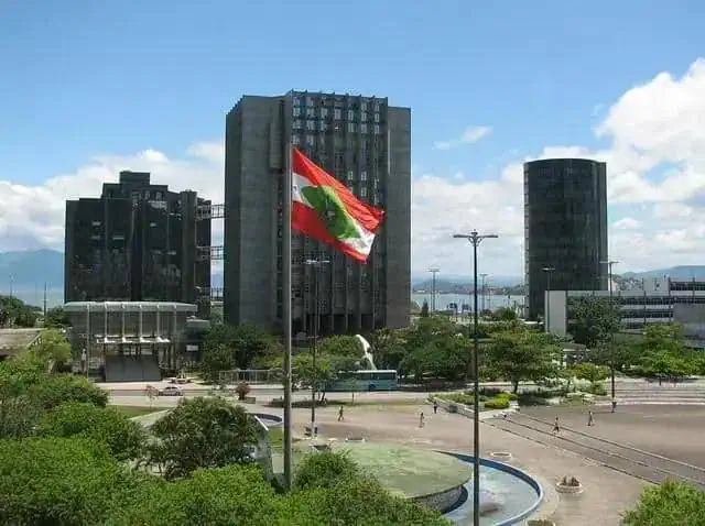 Bandeira do Pará em destaque na cidade de Belém, com edifícios modernos ao fundo e céu azul, representando o desenvolvimento e o crescimento econômico do estado.