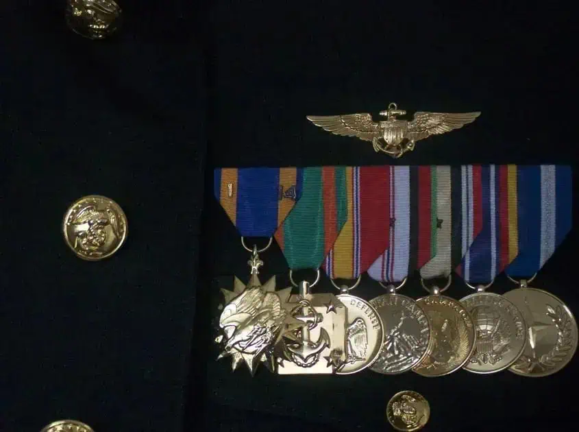 Medalhas militares e insígnia de alta patente com uniforme escuro, simbolizando honra, serviço e reconhecimento em direito e segurança pública.