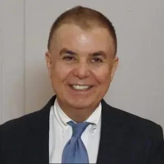 Homem de terno sorridente, apresentador ou advogado, em ambiente formal, representando notícias jurídicas e direitos, usado para ilustrar conteúdo do site Direito Hoje Notícias.