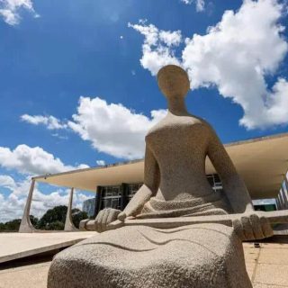 Estátua de justiça moderna em frente ao Congresso Nacional de Brasília, símbolo da luta pelos direitos e a justiça social no Brasil. Arquitetura contemporânea e cultura jurídica brasileira em destaque.