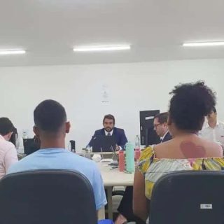 Audiência jurídica em uma sala de reuniões com profissionais do direito e clientes, abordando temas legais e judiciais.