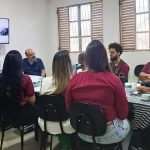Profissionais participam de reunião ou workshop em ambiente de escritório, com discussão e uso de tecnologia para atualização jurídica e notícias de direito, promovendo debates sobre temas relevantes na área jurídica.