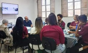Profissionais participam de reunião ou workshop em ambiente de escritório, com discussão e uso de tecnologia para atualização jurídica e notícias de direito, promovendo debates sobre temas relevantes na área jurídica.