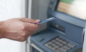 Cartão de débito sendo inserido em caixa eletrônico, transação bancária, tecnologia de pagamento digital, banco, operação financeira, segurança financeira, pagamento eletrônico, direito hoje notícias.