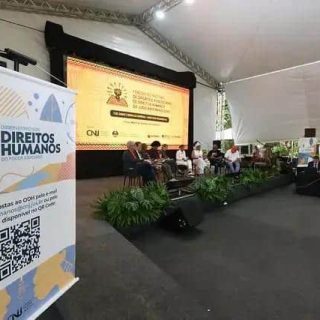 Direito Hoje Notícias evento de discussão de direitos humanos com painel de especialistas sob tenda ao ar livre.