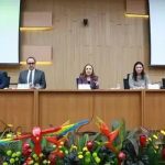 Profissionais participando de painel em evento jurídico com destaque para debates sobre direito e inovação, com banners do Direito Hoje Notícias ao fundo.